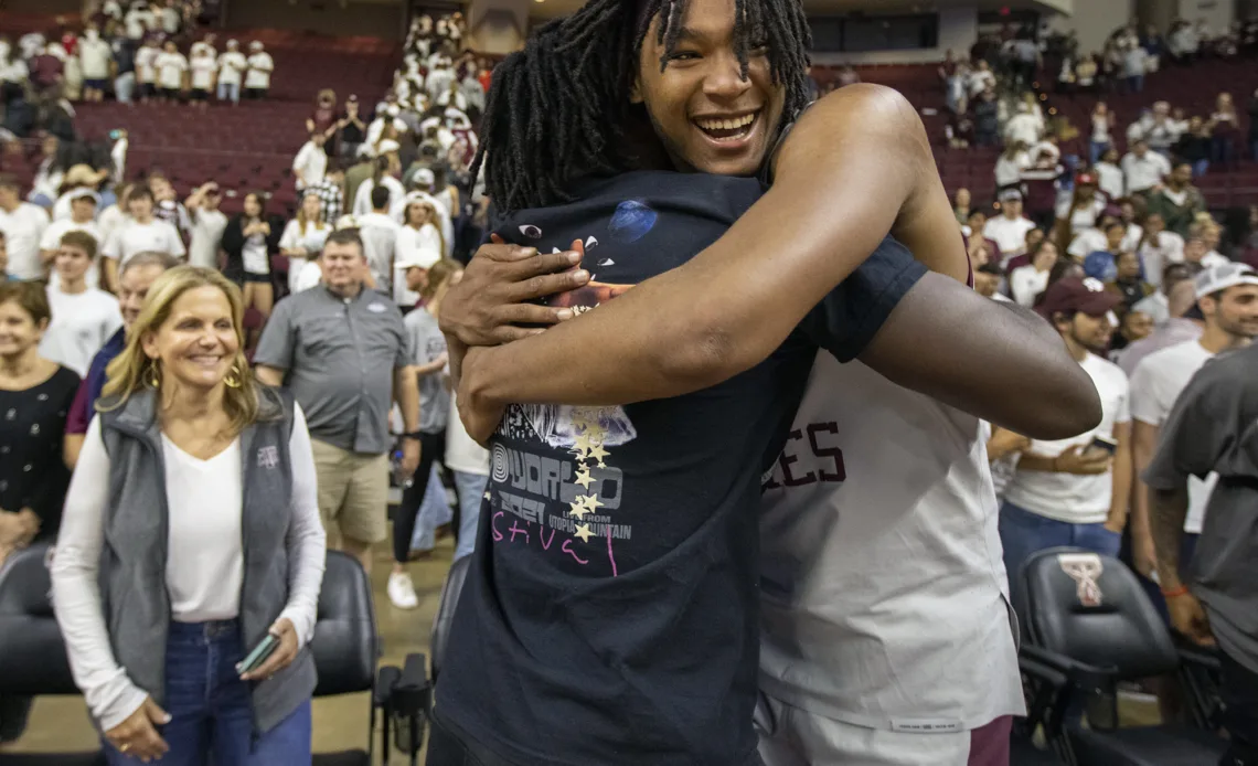 Texas A&M's Javonte Brown, facing, hugs former Texas A&M football tight end Jalen Wydermyer following a victory in an NCAA college basketball game against Wake Forest in the third round of the NIT in College Station, Texas, Wednesday, March 23, 2022. (Michael Miller/College Station Eagle via AP)