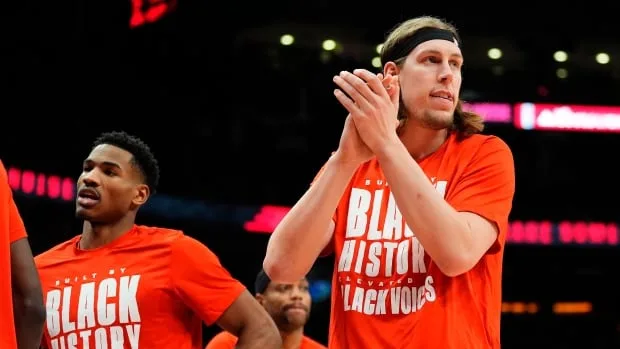 A basketball player in a red t-shirt claps his hands.